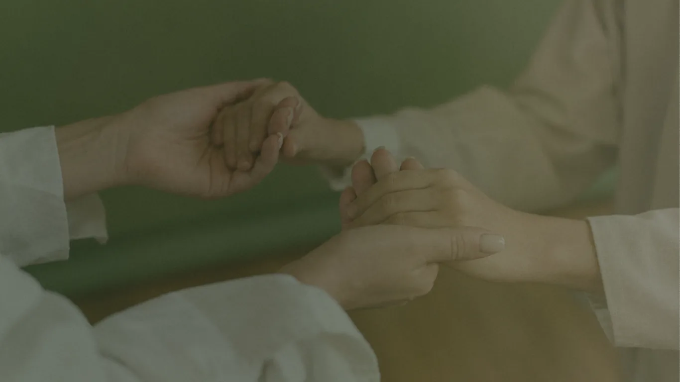 A wellness practitioner gently supporting a client's hands